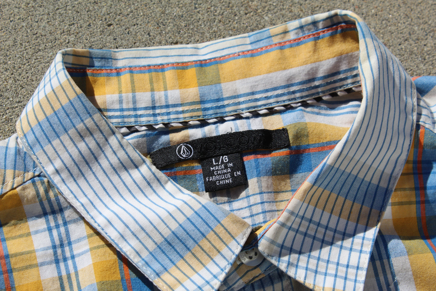 Plaid shirt with collar and label on a textured surface

